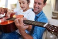 So you know this song. a father and his young son sitting together in the living room at home playing guitar. Royalty Free Stock Photo