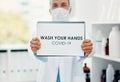 You know what you need to do. a scientist holding a sign with wash your hands on it in a laboratory.