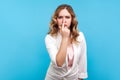 You are liar. Portrait of upset woman touching nose showing lie gesture and frowning face. blue background