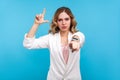 You are loser. Portrait of irritated woman doing loser gesture, L finger sign and pointing at camera. blue background