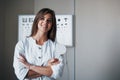 When you in love with your job. Beautiful female doctor standing in the office with hands crossed and pictures at Royalty Free Stock Photo