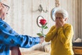 you are my Valentine - senior man giving a fresh red rose to his cute wife at home medium shot love and seniority Royalty Free Stock Photo