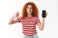 You need see. Attractive smiling joyful redhead curly blue-eyed girl 25s stylish blogger promote app device hold