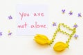 You are not alone message card handwriting with yellow flowers ylang ylang arrangement music score