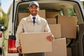 You order it, we deliver it. Portrait of a friendly delivery man unloading cardboard boxes from his van.