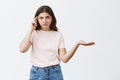 Are you out of your mind. Portrait of and annoyed bossy brunette female in pink t-shirt shrugging with one palm