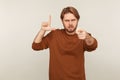 You`re loser! Portrait of angry bossy man with beard in sweatshirt showing loser gesture and pointing finger