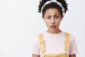 You say what. Portrait of confused and upset good-looking African American woman in headband and cute yellow overalls