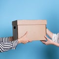 You send, transfer and accept a box with a parcel from hand to hand, a young woman receives a gift or delivery.