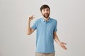 You should be happy even about small things. Portrait of cute bearded caucasian guy showing small gesture or shaping