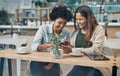 You should follow this funny vlogger. two friends looking at something on a cellphone while sitting together in a coffee Royalty Free Stock Photo