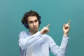 You should read this. Portrait of a young beautiful man wearing white t-shirt and blue shirt in headphones. Point to something top Royalty Free Stock Photo