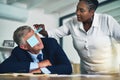 Are you sleeping under there. a businesswoman removing adhesive notes from her coworkers eyes as he sleeps at his desk.