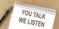 YOU TALK WE LISTEN text on a notepad with pen, business