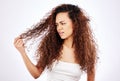 You think your lifes hard. a beautiful young woman looking frustrated with her hair while posing against a white