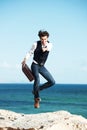 You too could have this freedom. Handsome young man holding a briefcase jumping in the air with the ocean in the Royalty Free Stock Photo