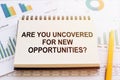 ARE YOU UNCOVERED FOR NEW  OPPORTUNITIES? - written on notepad on financial charts and graphs with yellow pen Royalty Free Stock Photo