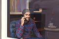 You wanna meet for coffee. A young man speaking on his cellphone while sitting in a coffee shop. Royalty Free Stock Photo