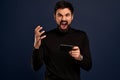 You will have problems man. Portrait of angry confused aggressive in bad mood guy shouting threatening, man holding mobile phone