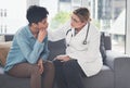 You will overcome this...a compassionate young female doctor consoling a female patient while sitting on the couch in