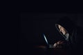 You wont even see him coming. a hooded computer hacker using a laptop in the dark. Royalty Free Stock Photo