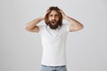 Are you in your mind, how could you do it. Portrait of mad and angry adult man with long curly hair and beard holding