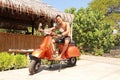 Youg Indonesia man is sitting on orange Classic Vespa. Orange Classic Vespa. A old orange Vespa Super motorscooter is parked on a