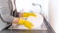 Yougn housewife in rubber gloves washing dishes in sink on kitchen Royalty Free Stock Photo