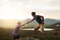 Youll aways find a helping hand on the trail. a friendly young hiker helping his friend climb onto a rock on a mountain Royalty Free Stock Photo