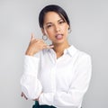 Youll want to hear what I have to say. Studio shot of a confident young businesswoman making a call me gesture against a Royalty Free Stock Photo