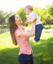 Youmg happy woman playing with her cute baby in summer sunny park outdoor