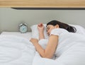 Youn and beautiful black long hair Asian woman deeply sleeping on bed in bedroom bedside alarm clock