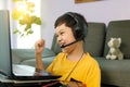 Youn little cute Asian 10s boy wearing headphones sitting in home living room using laptop notebook computer for online distance Royalty Free Stock Photo