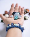 Yound woman is holding a collection of blue raw mineral gemstones in her palm