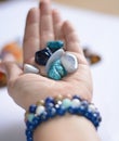 Yound woman is holding a collection of blue raw mineral gemstones in her palm