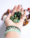 Yound woman is holding a collection of green raw mineral gemstones in her palm