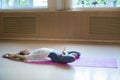 Young acrobatic woman with blonde hair sitting on the yoga mat in lotus pose and leaning back