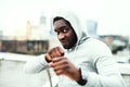 Young active black sportsman in boxing position in a city, wearing hoodie.