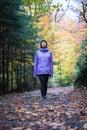 Young active caucasian woman standing in the middle of a path in a colourful forest looking up on a rainy day during Fall Royalty Free Stock Photo