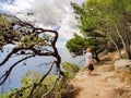 Young active feamle tourist taking a break, drinking water, wearing small backpack while walking on coastal path among Royalty Free Stock Photo