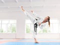 Girl wearing in white kimono performing martial arts high kick skill. Royalty Free Stock Photo