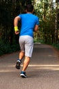 Young active handsome male healthy runner jogging outdoors along a scenic path in a forest. Vertical shot. Royalty Free Stock Photo