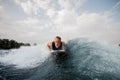 Young active man lying on the white wakeboard on the blue wave Royalty Free Stock Photo