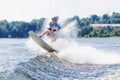 Young active man riding wakeboard on a wave from a motorboat on summer lake Royalty Free Stock Photo