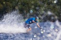 Young active man riding wakeboard on a wave from a motorboat on summer lake Royalty Free Stock Photo