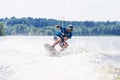 Young active man riding wakeboard on a wave from a motorboat on summer lake Royalty Free Stock Photo