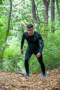 Young active muscular man in sportswear running through the footpath in nature in the forest for cardio workout vertical image
