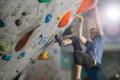 Young active sport caucasian man with beard and glasses climbing on gym wall during bouldering workout Royalty Free Stock Photo