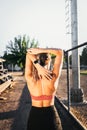 young active sport woman seen from the back stretching triceps beside of the running track Royalty Free Stock Photo