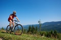 Cyclist in helmet, sunglasses and full equipment riding bike on grassy hill Royalty Free Stock Photo